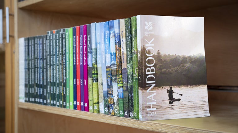 A row of National Trust handbooks lined up on a bookshelf